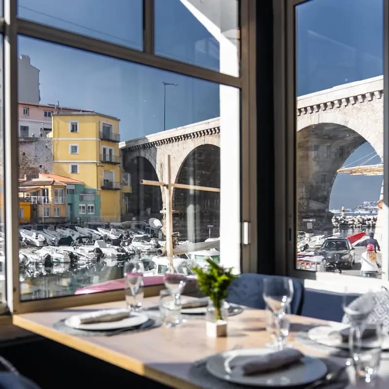 Table at Chez Fonfon overlooking the Vallon des Auffes in Marseille: boats, colourful houses and a stone bridge