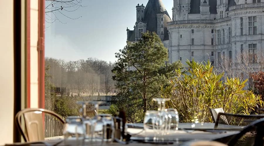 Le Saint-Louis terrace facing the Château de Chambord, glasses on a set table