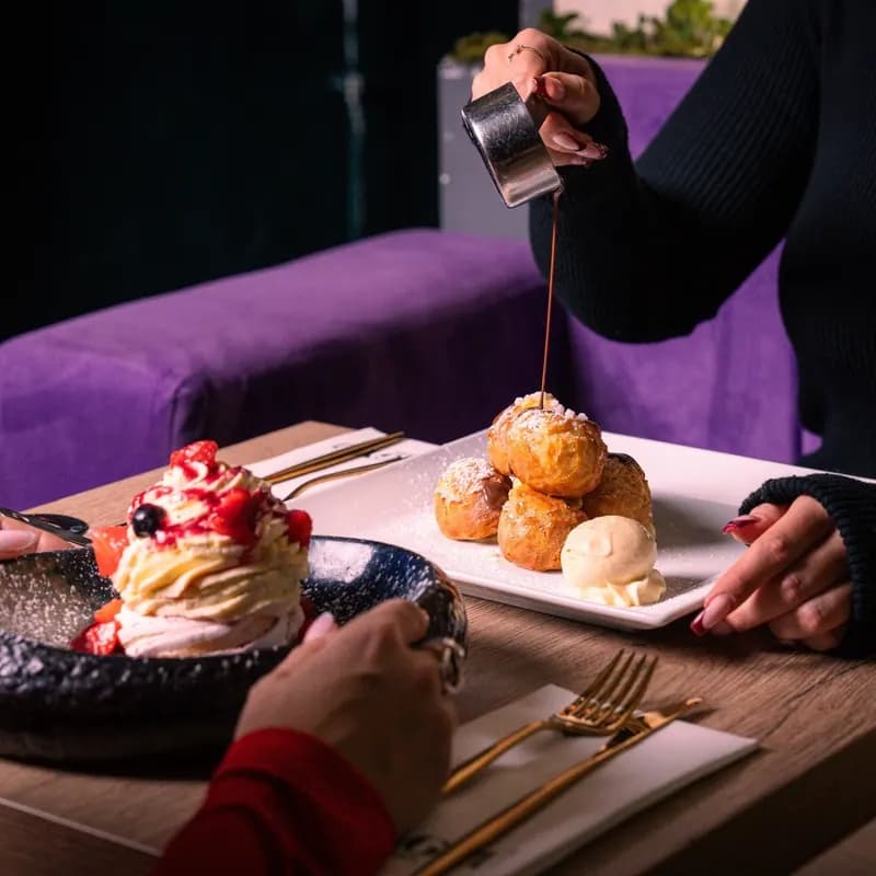 Chocolate-drizzled profiteroles and a red-fruit pavlova served at Le Wagyu, in Paris