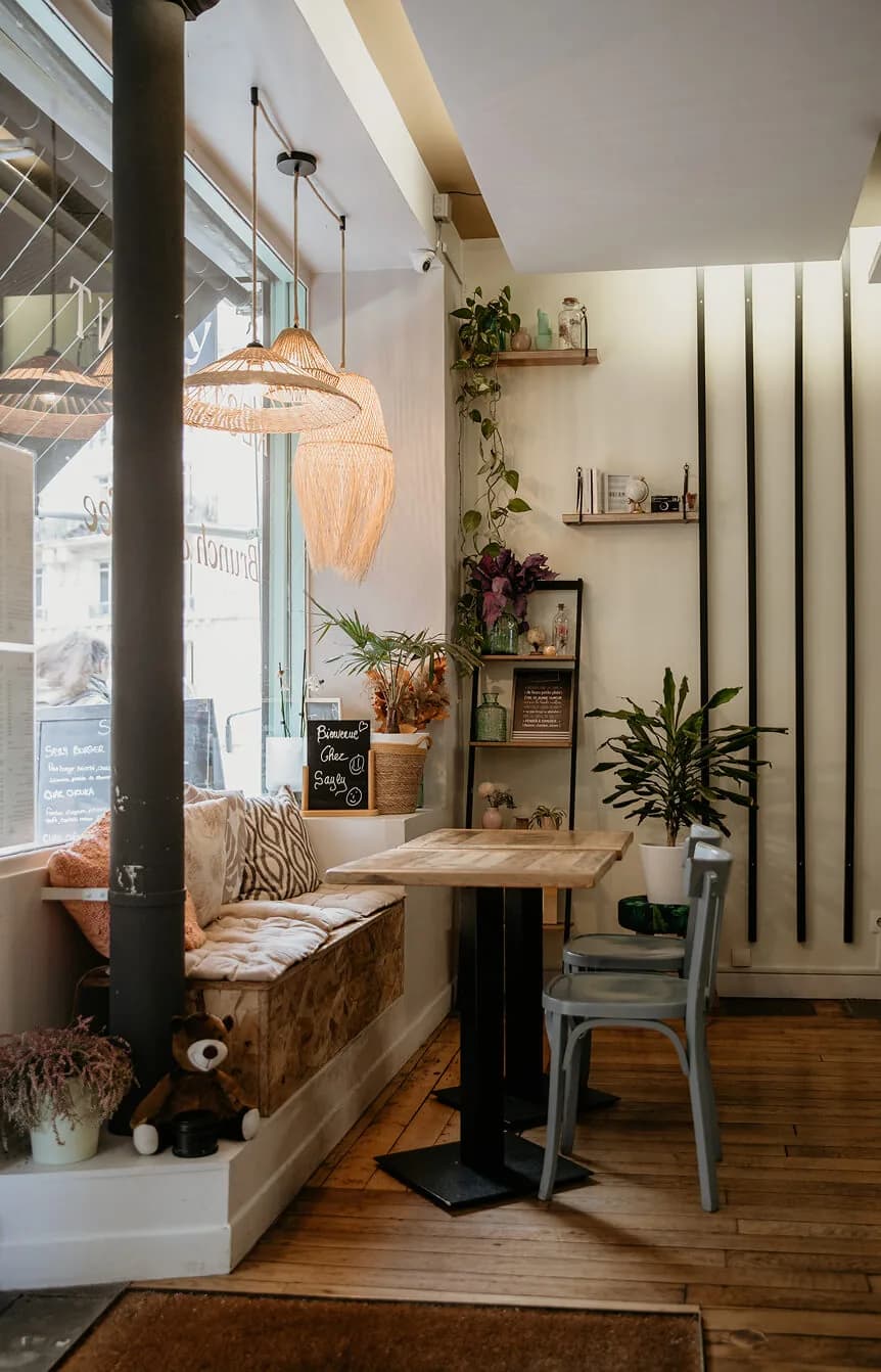 Salle chaleureuse d’un restaurant parisien, banquette et petites tables en bois