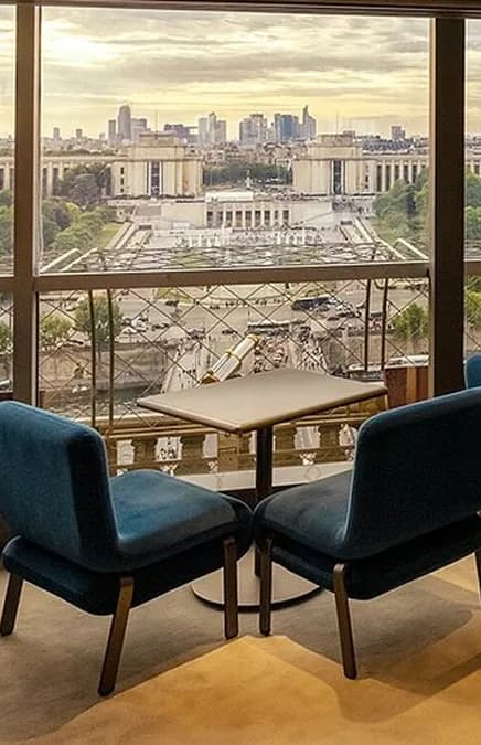 Salle de Madame Brasserie : deux fauteuils bleus face à une baie vitrée qui donne sur le Trocadéro